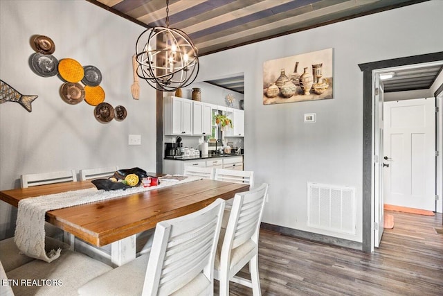 dining room featuring hardwood / wood-style flooring, sink, a chandelier, and beamed ceiling