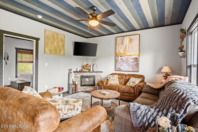 living room with a stone fireplace and ceiling fan