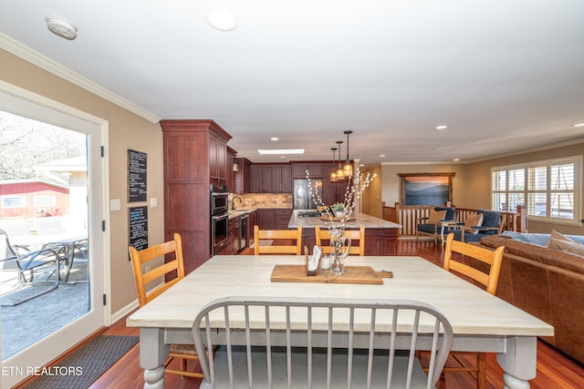 dining area with hardwood / wood-style floors, ornamental molding, and a chandelier