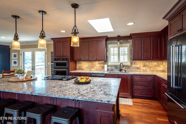 kitchen featuring sink, double oven, light stone countertops, decorative light fixtures, and high end refrigerator