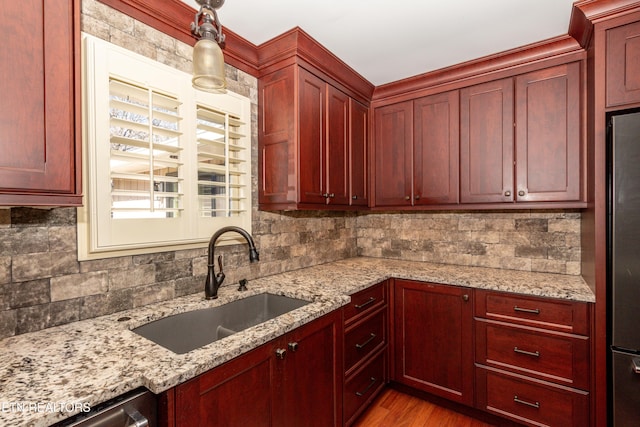 kitchen with pendant lighting, sink, decorative backsplash, and light stone countertops