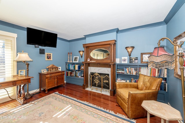 living area with dark hardwood / wood-style flooring, crown molding, and a high end fireplace