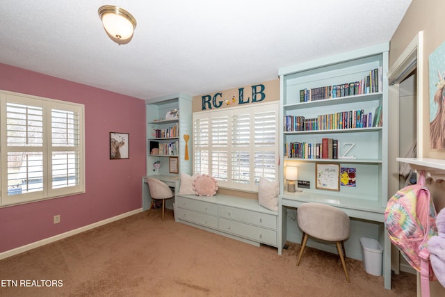 carpeted office space with built in desk and a textured ceiling