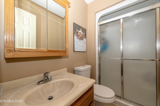 bathroom with vanity, toilet, and a shower with shower door