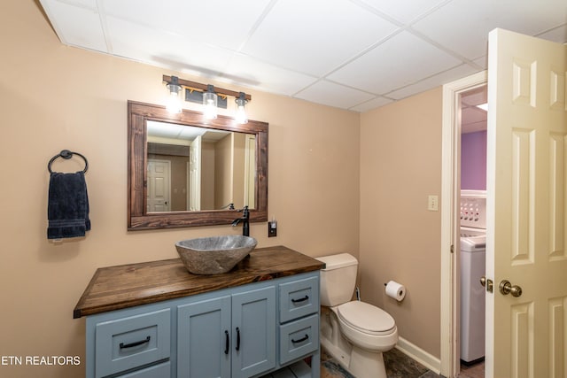 bathroom featuring a drop ceiling, washer / clothes dryer, vanity, and toilet