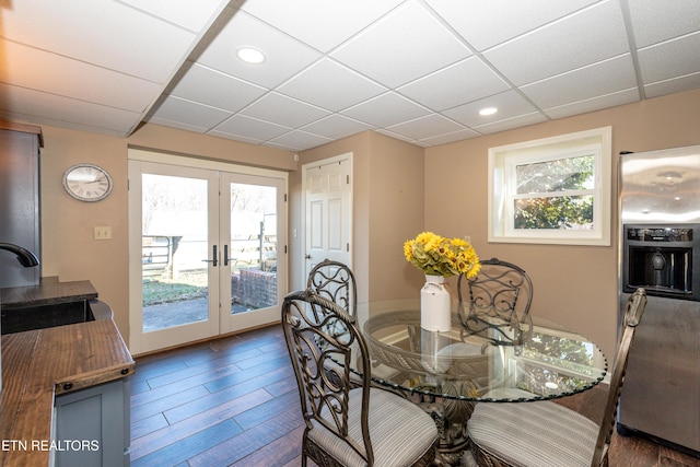 dining room with dark wood-type flooring, sink, french doors, and a drop ceiling