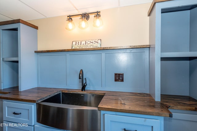 kitchen with blue cabinets, sink, and butcher block countertops