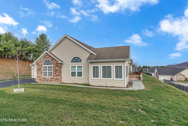 back of property with a yard, roof with shingles, and fence