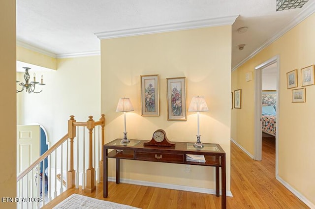 hallway with an inviting chandelier, ornamental molding, and light wood-type flooring