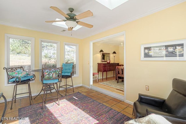 living area with crown molding, a skylight, tile patterned floors, and ceiling fan