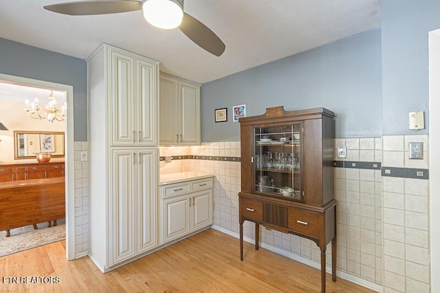 interior space with tile walls, light hardwood / wood-style flooring, and ceiling fan