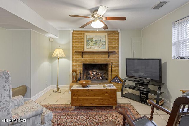 living room featuring crown molding, ceiling fan, a fireplace, and light tile patterned floors