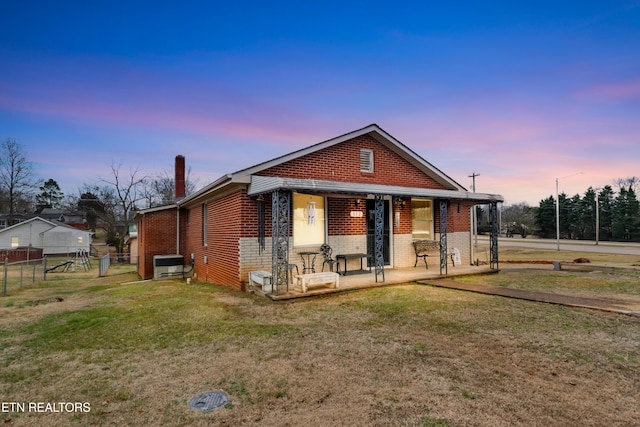 view of front of property featuring a front yard, brick siding, fence, and a chimney