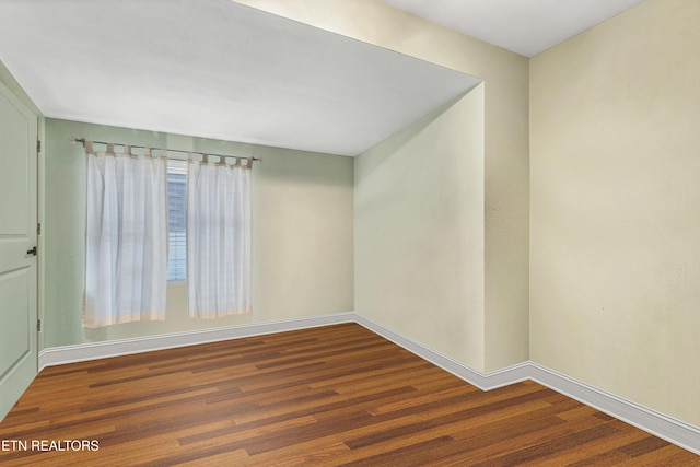 unfurnished room with dark wood finished floors and baseboards