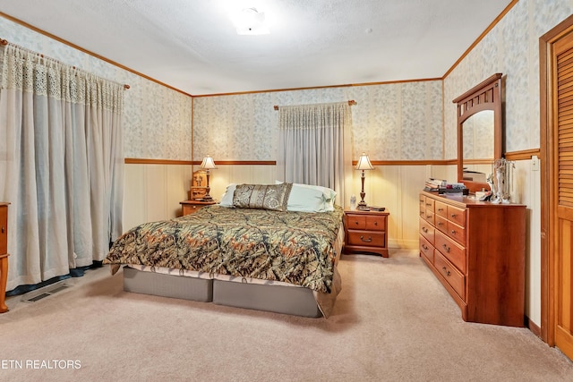 bedroom featuring crown molding, visible vents, wainscoting, light carpet, and wallpapered walls