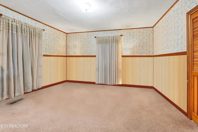 spare room featuring a textured ceiling, carpet floors, visible vents, and wallpapered walls