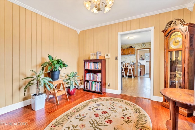 sitting room featuring a chandelier, ornamental molding, wood finished floors, and baseboards