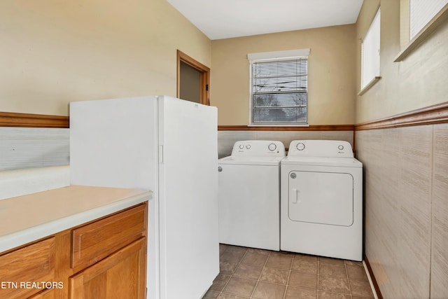 laundry area with light tile patterned flooring, laundry area, a wainscoted wall, and separate washer and dryer