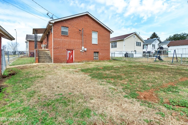 back of house with a yard, brick siding, and a fenced backyard