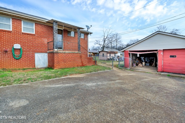 view of side of property with a garage, brick siding, fence, and an outdoor structure