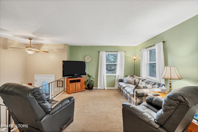 carpeted living room featuring ceiling fan and a textured ceiling