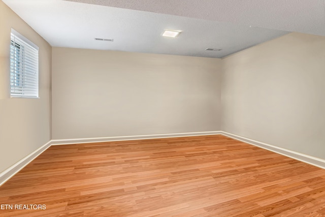 empty room with light hardwood / wood-style floors and a textured ceiling