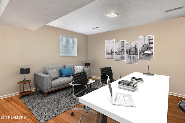 home office featuring wood-type flooring and a textured ceiling