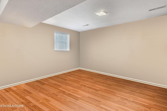 spare room featuring hardwood / wood-style floors and a textured ceiling