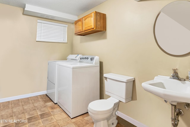 clothes washing area featuring sink, washing machine and dryer, and a textured ceiling