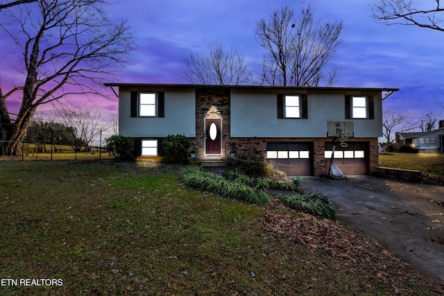 raised ranch featuring a garage and a lawn