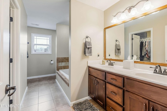 bathroom featuring tile patterned flooring, vanity, and tiled bath