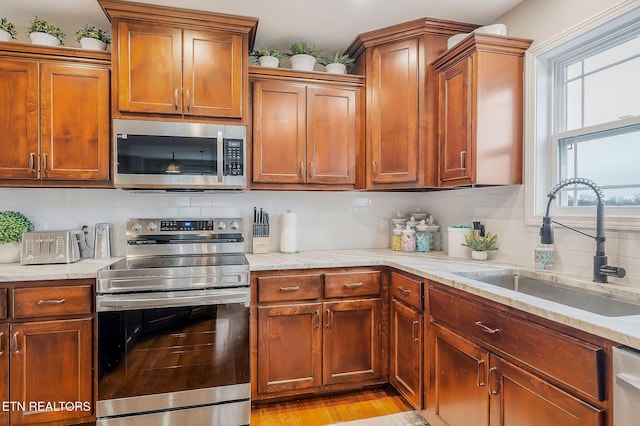 kitchen featuring stainless steel appliances, light stone countertops, sink, and backsplash