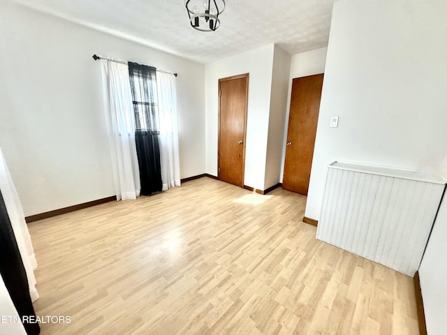 empty room with radiator heating unit, light hardwood / wood-style flooring, and a textured ceiling