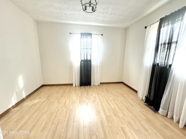 empty room with a textured ceiling and light wood-type flooring