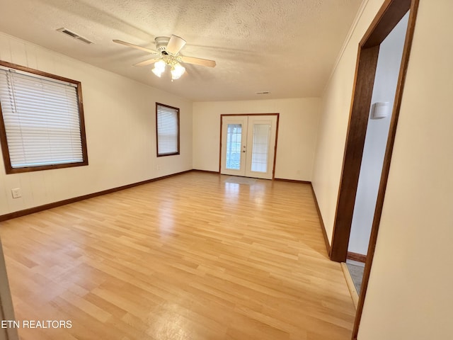 spare room with ceiling fan, a textured ceiling, light wood-type flooring, and french doors