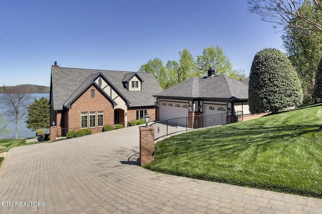 view of front facade featuring a water view, a garage, and a front lawn