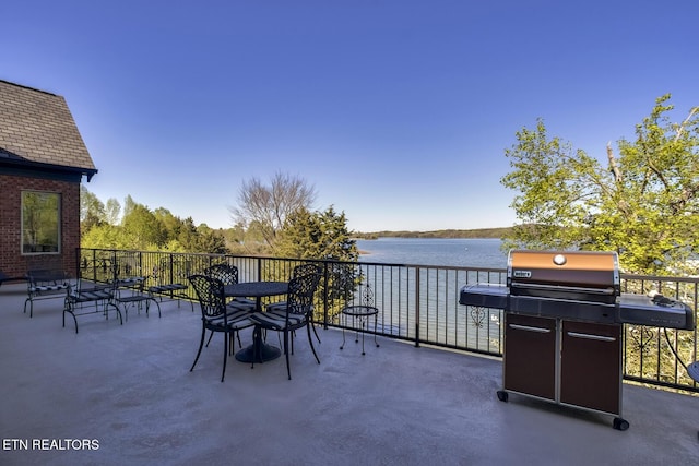 view of patio with grilling area, a balcony, and a water view