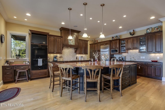 kitchen featuring pendant lighting, a kitchen island with sink, built in appliances, dark brown cabinetry, and custom range hood