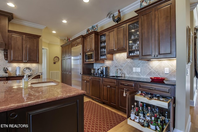 kitchen featuring crown molding, sink, built in appliances, and dark brown cabinetry