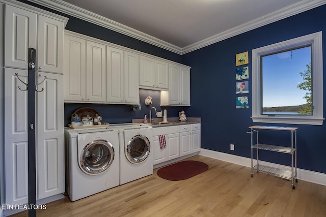 laundry room with sink, crown molding, cabinets, washer and dryer, and light hardwood / wood-style floors