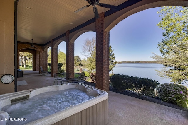 view of patio / terrace with a hot tub, a water view, and ceiling fan