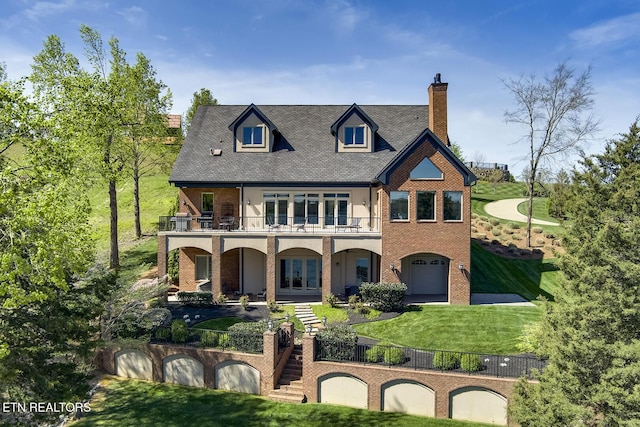 rear view of property featuring a garage, a lawn, and a balcony