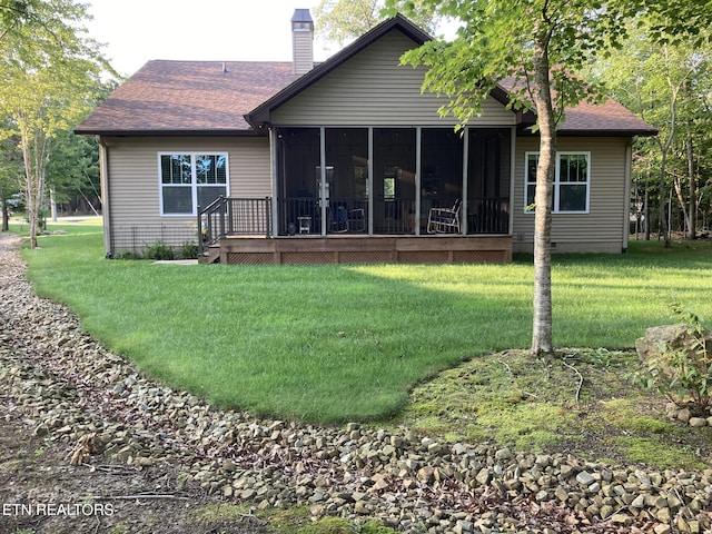 rear view of house featuring a yard and a sunroom