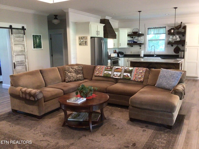 living room with sink, ornamental molding, a barn door, and hardwood / wood-style floors