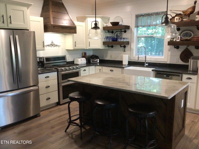 kitchen with pendant lighting, sink, white cabinets, custom exhaust hood, and stainless steel appliances