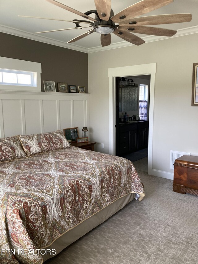 bedroom with ornamental molding, carpet floors, ensuite bathroom, and ceiling fan