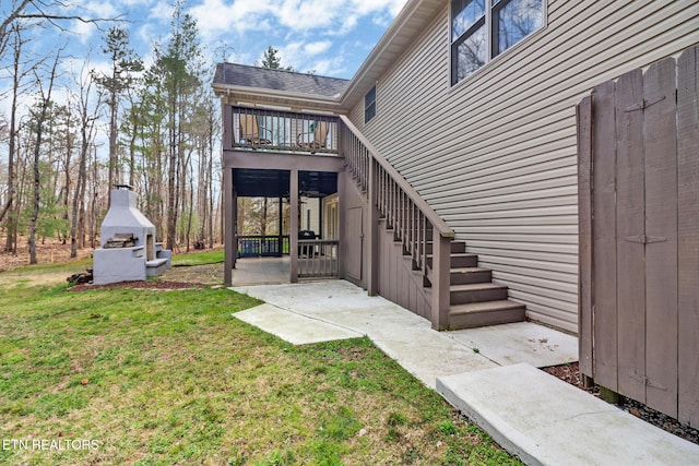 back of house with a lawn, a fireplace, a balcony, stairs, and a patio area