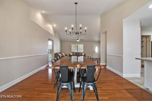 dining area featuring baseboards, lofted ceiling, a notable chandelier, and wood finished floors