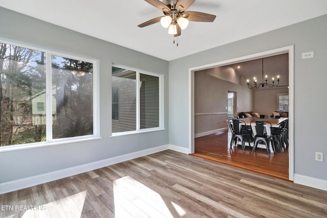 dining space featuring a wealth of natural light, baseboards, wood finished floors, and ceiling fan with notable chandelier