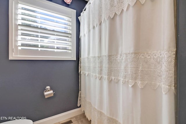 full bathroom featuring tile patterned flooring, a shower with shower curtain, and baseboards